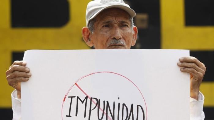 A man holds a banner that reads "impunity", during a protest outside the Special Military Security Unit base in San Salvador, August 24, 2011.